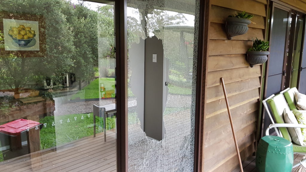 Sliding door with a black frame has exploded into pieces after being hit with a stone from the mower